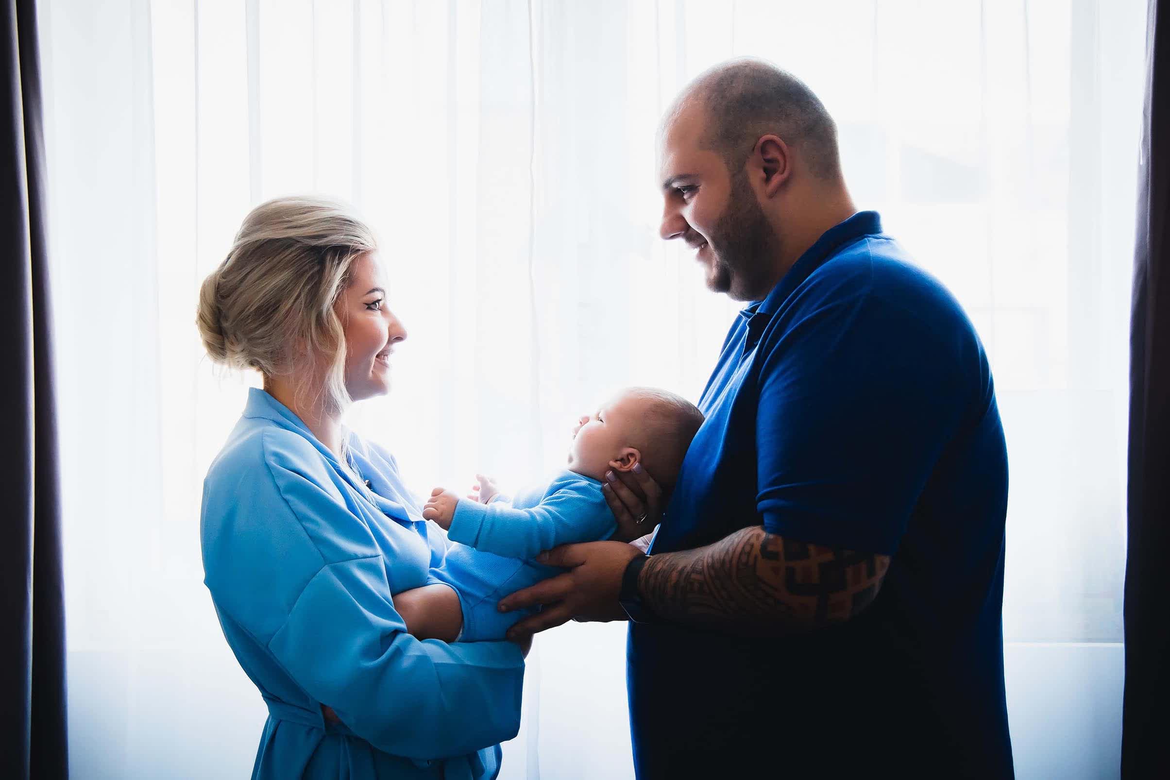 mama si tata zambind cu copilul in brate la sedinta foto botez